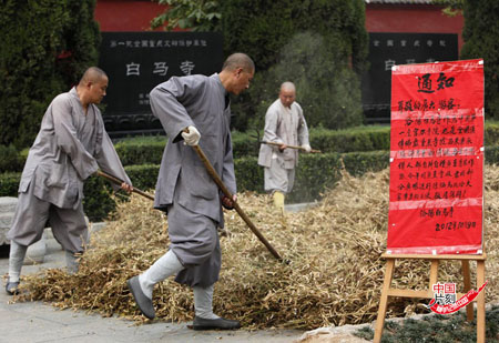 2012年10月11日，河南洛阳，白马寺里，几十位身着僧袍的和尚拿着农具，在广场上忙着晾晒黄 豆荚。