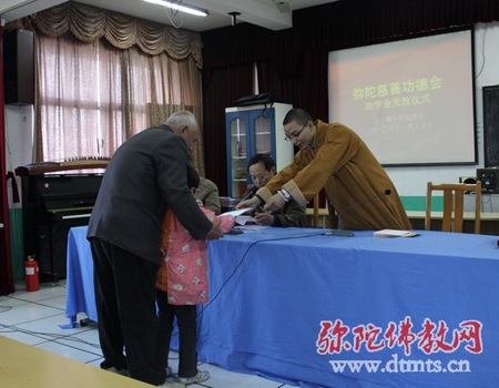 弘明师亲手将助学款递到贫困家庭学子手中，并鼓励孩子们好好学习长大后报效社会和人民