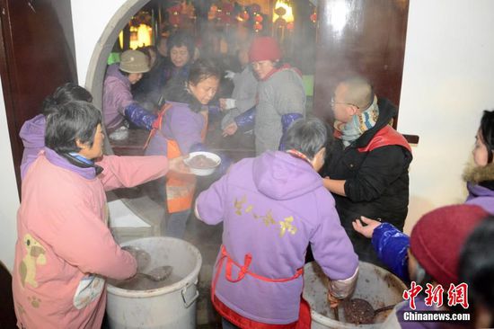 1月27日，民众纷纷前往寒山寺领取免费的腊八粥。当日是中国传统的民俗节日腊八节，苏州寒山寺为进寺的游客市民免费提供该寺熬制的腊八粥，吸引了众多市民前来领取，祈愿新年和合美满。图为寺庙义工为市民盛粥。